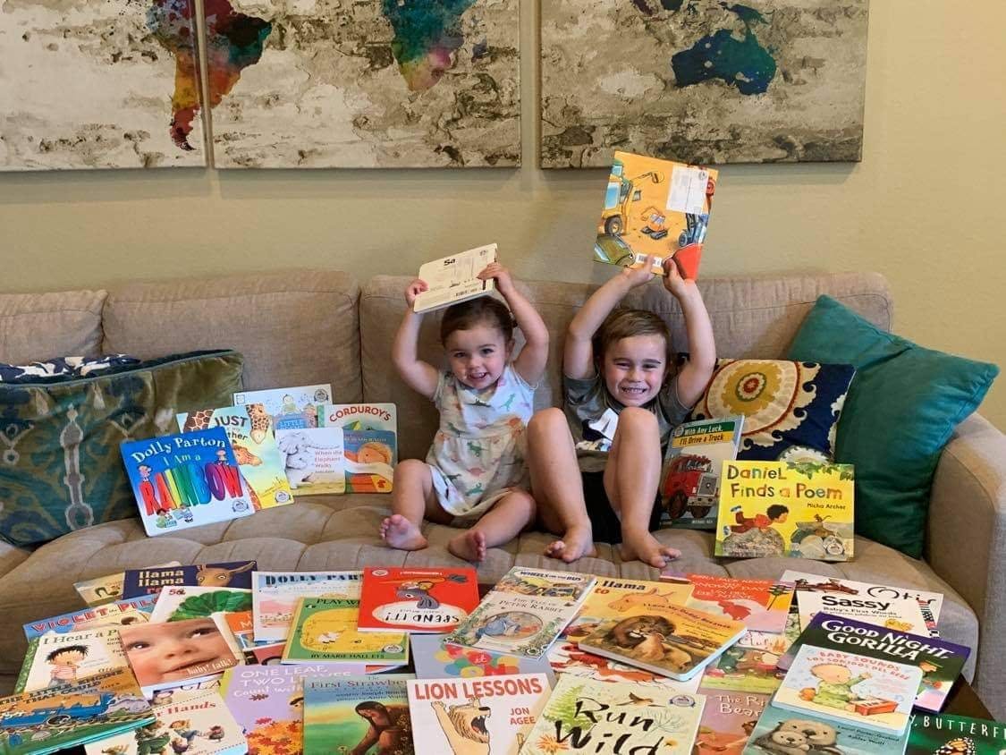 Two young children on a couch surrounded by their Dolly Parton Imagination Library books